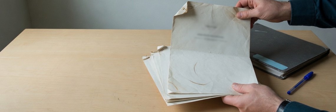 Maos folheando um contrato de varias paginas sobre a mesa
